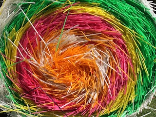 A massive multicolored bundle of plastic straws in a swirl pattern